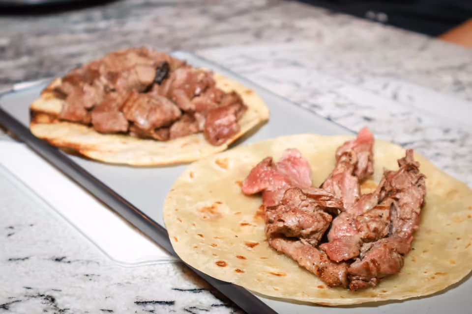 Dos tacos de carne asada en tortilla de harina, servidos en una tabla